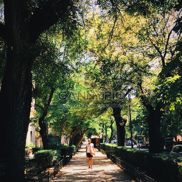 Girl walking in the street with green trees - image gratuit #271685 
