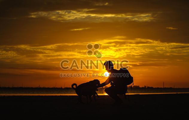 silhouette of man and dog at sunset - image #303985 gratis