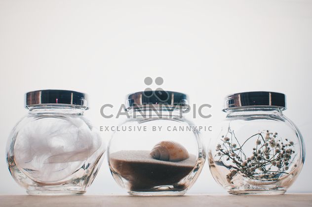 Small jars with decorations on white background - бесплатный image #342545