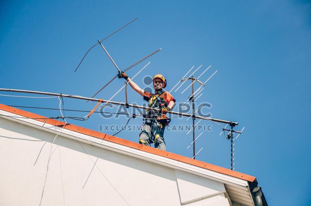 Worker installing antenna on roof top - бесплатный image #344535