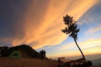 Tourists near tent under cloudy sky at sunset - бесплатный image #344605
