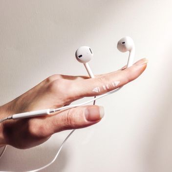 White earphones in female hand - image gratuit #345055 