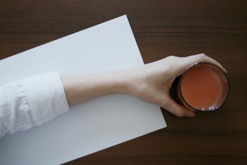 Glass of juice in hand on wooden table - image #348675 gratis