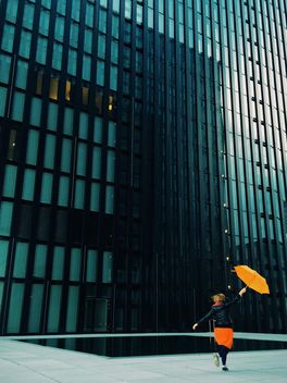Woman with orange umbrella on a background of modern building facade - бесплатный image #439115