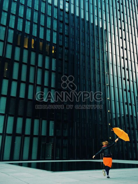 Woman with orange umbrella on a background of modern building facade - Kostenloses image #439115