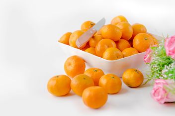 oranges in white plate with knife and pink flowers on white background - Free image #452515