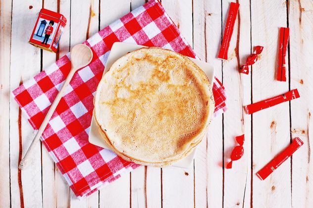 Pancakes, wooden spoon and checkered dishcloth on wooden background - Free image #136445