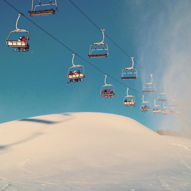 Snowy ski lift against the sky lifts skiers on the mountain - image #198835 gratis