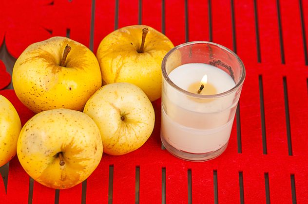 Yellow apples and candle on red background - Free image #272525