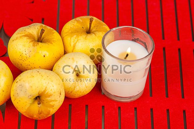 Yellow apples and candle on red background - бесплатный image #272525