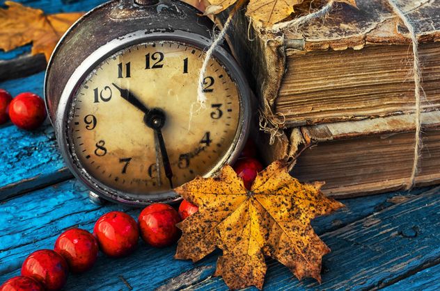 Old alarm clock, old books, beads and yellow autumn leaves on blue wooden background - Free image #302085