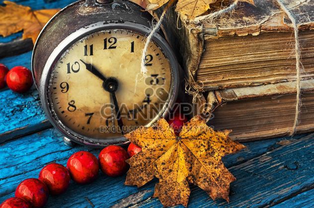Old alarm clock, old books, beads and yellow autumn leaves on blue wooden background - бесплатный image #302085