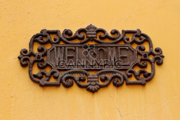 old welcome sign on the yellow wall - image #304075 gratis