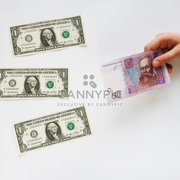American money on the table and Ukrainian money in hand on a white background - бесплатный image #329225