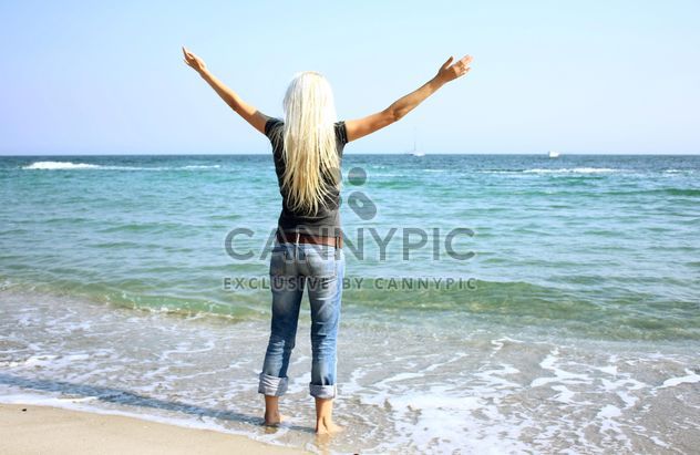Young blond woman standing aback on sea shore - Kostenloses image #344075