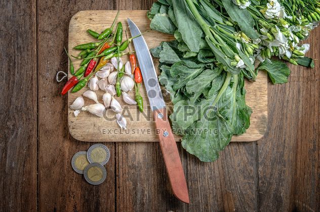 garlic and chili peppers on a wooden desk near coins on the table - image gratuit #452535 