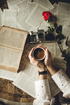 Woman holding hot coffee. Old book, analog camera and a red rose from above. - Free image #478165